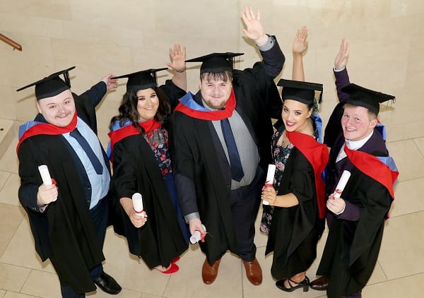 Graduates in gowns on graduation day celebration.